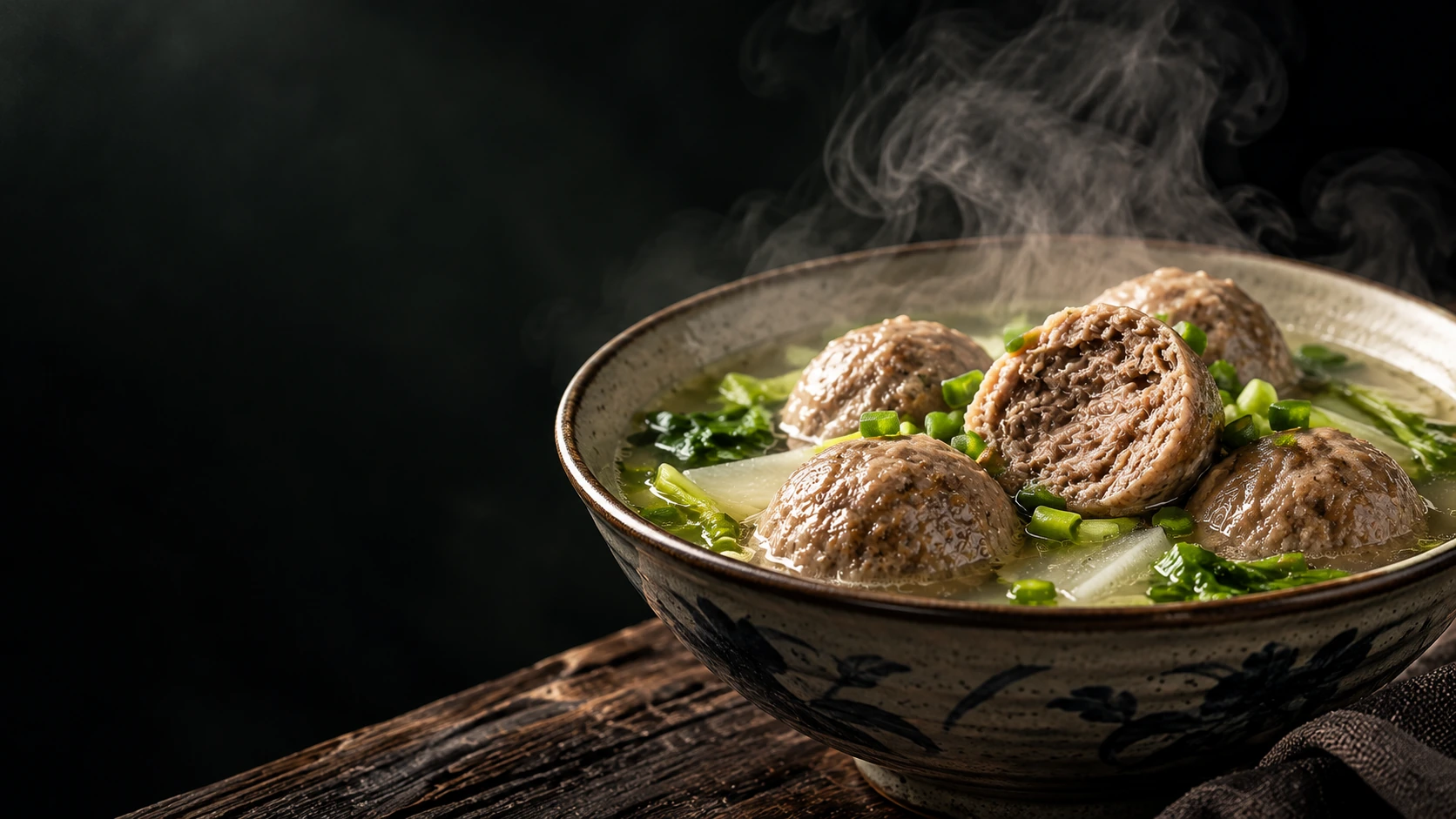 Editorial illustration of a steaming bowl of beef balls, one cut open, with greens