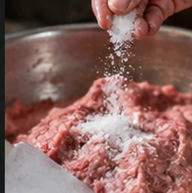 Illustrative close-up of seasoning added to meat paste in a mixing bowl